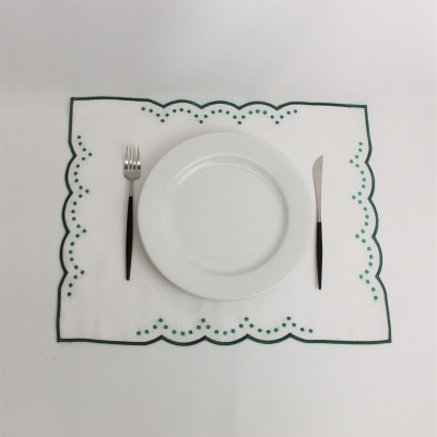 Jogo americano branco com borda verde e padrão de pontos com prato e talheres