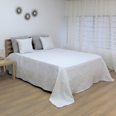 Cama com colcha branca, almofadas cinza/branco, cabeceira madeira clara, cortinas transparentes brancas