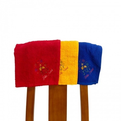 Toalhas de banho coloridas com bordado 'Feliz Natal' numa estrutura de madeira