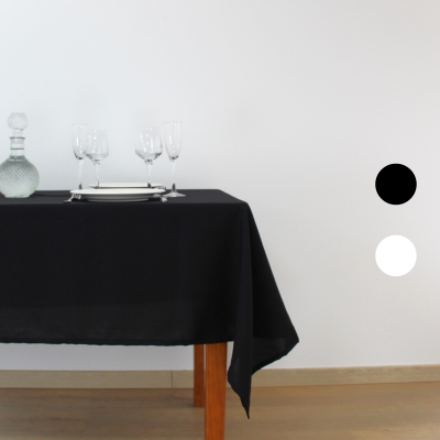 Toalha de mesa preta sobre mesa de madeira com copos, pratos e garrafa de vidro