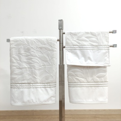 Três toalhas brancas com padrão de folhas num suporte metálico