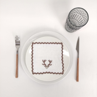 Conjunto de talheres com cabo de madeira ao lado de prato com guardanapo bordado e copo transparente