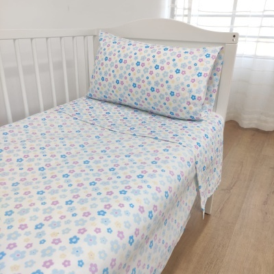 Lençóis com padrão floral em cama branca numa divisão clara