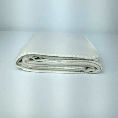 Manta branca dobrada com borda decorativa sobre superfície branca