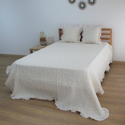 Cama com colcha branca texturizada e duas almofadas correspondentes