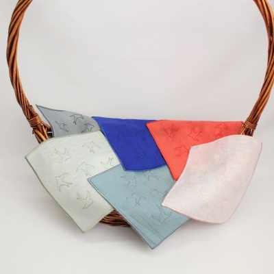 Cinco toalhetes de tecido coloridos com padrão de pássaros numa cesta de verga