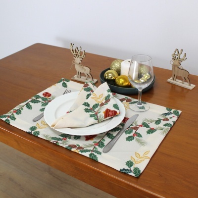 Mesa de madeira com individual e guardanapo estampados, prato branco, talheres, copo de vidro e decoração de veados de madeira e bolas douradas.