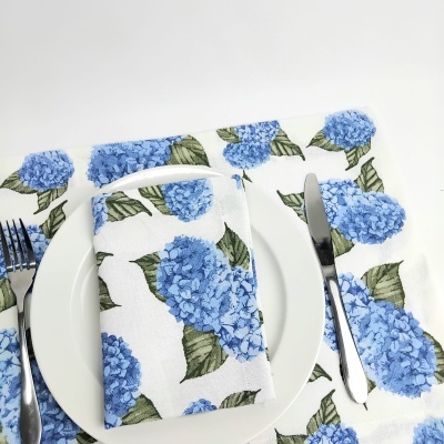 Jogo americano e guardanapo com estampa de flores azuis sobre prato branco