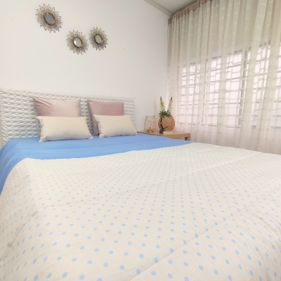 Quarto com cama feita com lençol azul e edredão branco com bolinhas azuis.