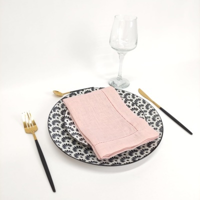 Conjunto de jantar com pratos preto e branco, guardanapo rosa e talheres preto e dourado