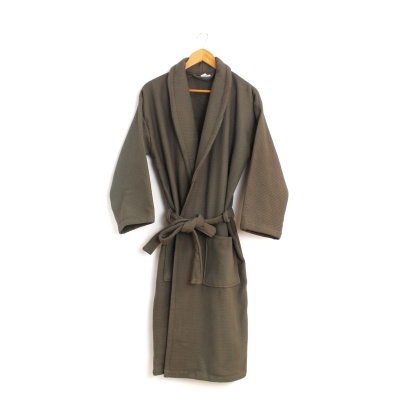 Robe banho verde-oliva texturizado pendurado num cabide de madeira