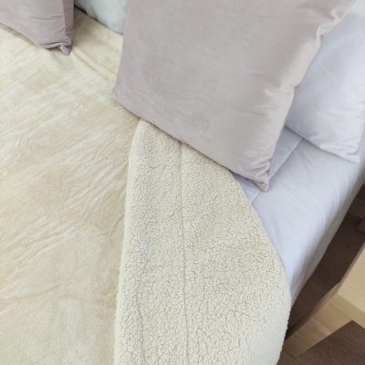 Colcha ou manta bege clara com textura pelúcia em cama com almofadas castanhas claras