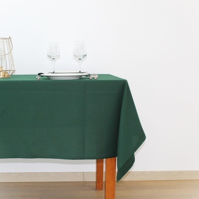 Mesa de madeira com toalha verde, copos, prato e talheres