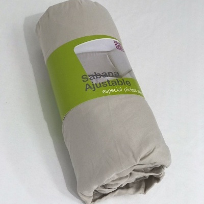 Sábana ajustable beige con embalaje verde sobre fondo blanco