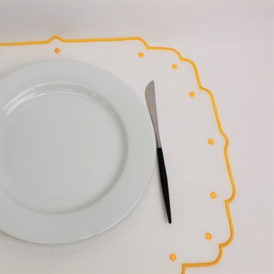 Prato branco em toalhete branco com bordas amarelas e faca de cabo preto