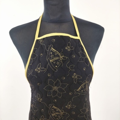Avental de cozinha preto com padrão dourado de flores, sinos e bagas, com acabamento em fita amarela