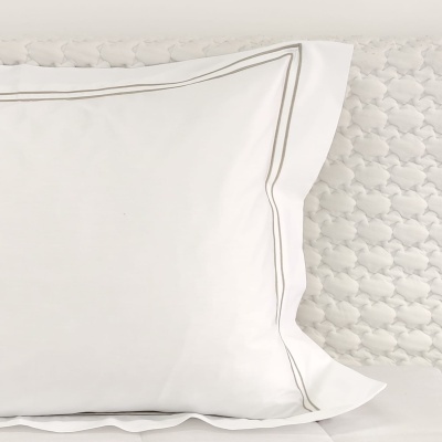 Travesseiro branco com fronha bordada e superfície texturizada branca