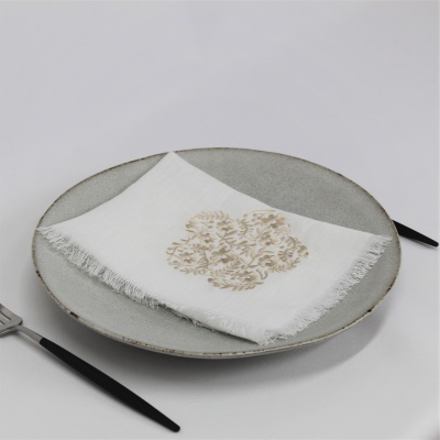 Prato cinzento com guardanapo branco decorado e talheres com cabos pretos