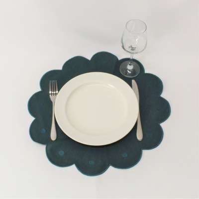 Prato branco com talheres e copo sobre individual azul em forma de flor