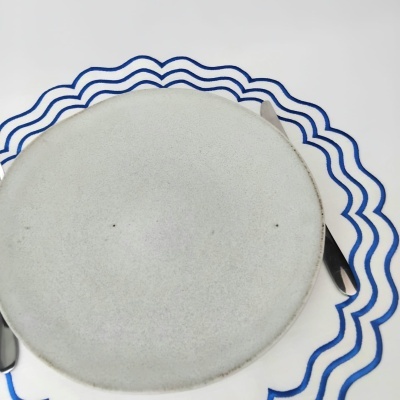 Prato cinzento claro sobre guardanapo branco com ondas azuis