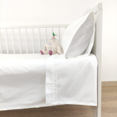 Cama branca com roupa de cama branca e peluche de alho