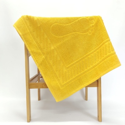 Toalha de banho amarela com pegadas em tecido sobre suporte de madeira