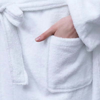 Robe de banho branca felpuda com cinto e bolso frontal.