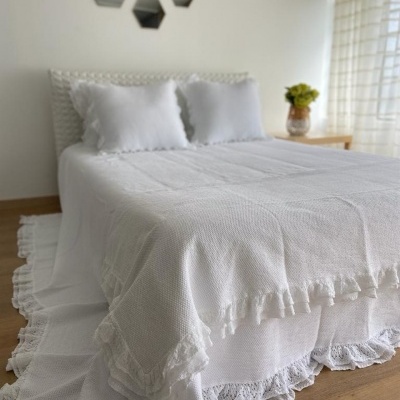 cama de casal com colcha branca rendilhada e duas almofadas brancas