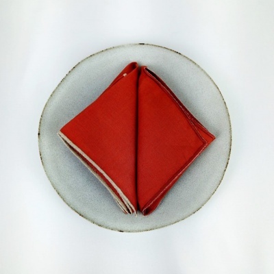 Guardanapo vermelho dobrado num prato de cerâmica cinzento