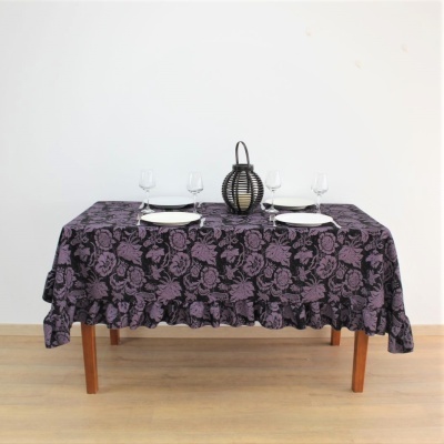 Mesa com toalha floral roxa e preta, pratos, copos e castiçal