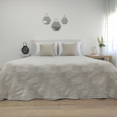 Cama com colcha bege texturizada e almofadas em quarto minimalista com decoração neutra