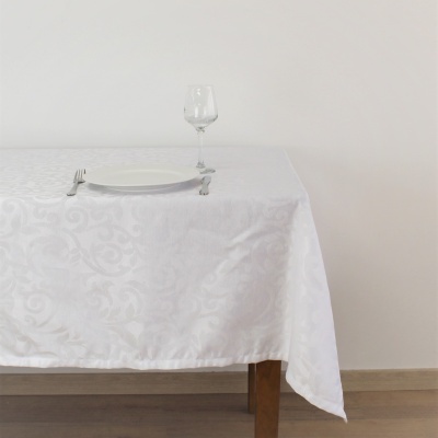 Mesa com toalha branca, prato, talheres e taça de vidro