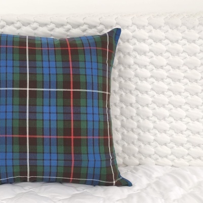 Almofada xadrez azul, verde e vermelho sobre superfície branca acolchoada