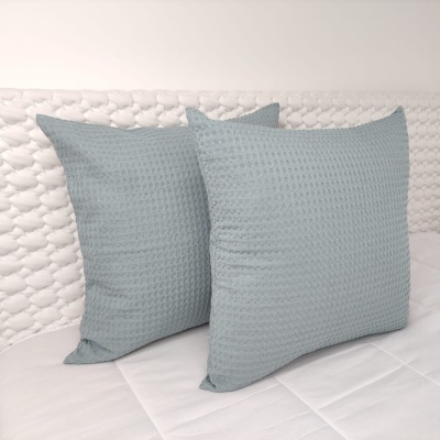 Almofadas verdes texturizadas sobre colchão branco com cabeceira acolchoada branca