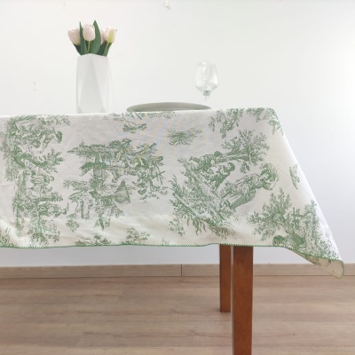Toalha de mesa branca com estampado verde em mesa de madeira decorada com vaso branco e flores cor-de-rosa
