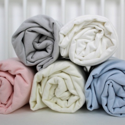 Cinco mantas enroladas em tecido macio e liso de cores pastel