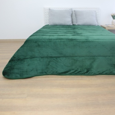 Edredão verde macio numa cama com cabeceira branca e almofadas cinzentas