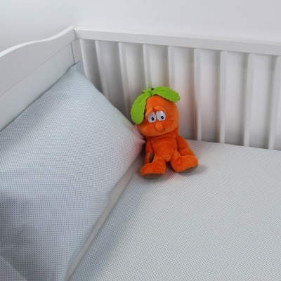 Berço branco com colchão cinza e peluche laranja em forma de cenoura