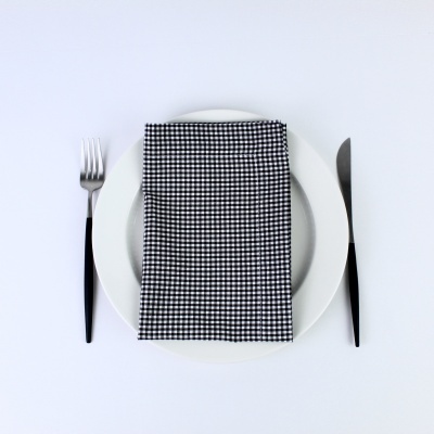 talheres com faca, garfo, prato branco e guardanapo quadriculado negro e branco