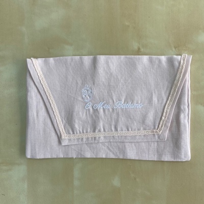 Lenço branco com bordado e renda sobre fundo verde claro.