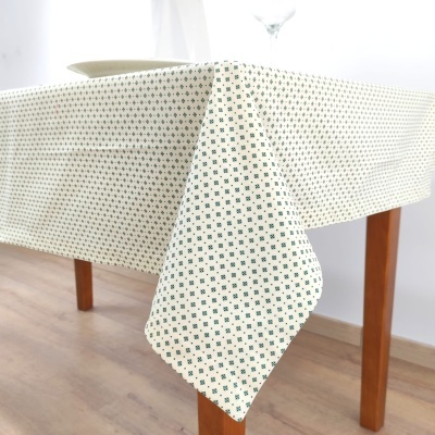 Toalha de mesa branca com padrão verde em mesa de madeira