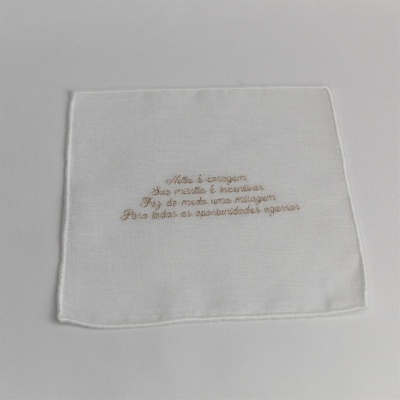 Pano branco com bordado bege de texto em língua portuguesa