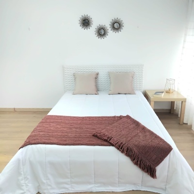 Cama de casal com manta castanha e mesa-de-cabeceira em ambiente minimalista
