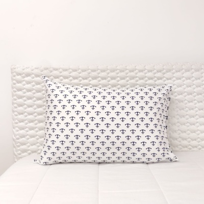 Almofada branca com âncoras azuis sobre cama branca acolchoada