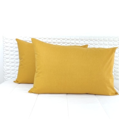 Três almofadas amarelo mostarda sobre superfície branca acolchoada
