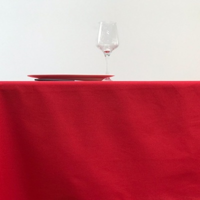 Mesa com toalha vermelha, prato vermelho, taça de vinho e cadeira de madeira
