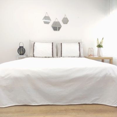 Quarto com cama de casal e decoração minimalista branca e castanha