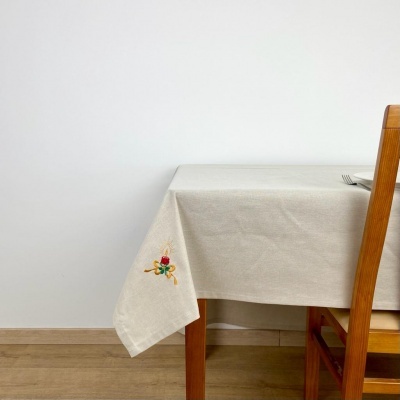 Toalha de mesa bege com bordado colorido numa mesa de madeira com cadeira wooden