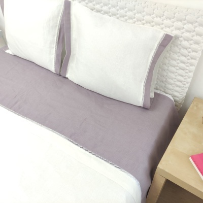 Conjunto de cama branco e lilás com cabeceira branca acolchoada e mesa de cabeceira em madeira clara
