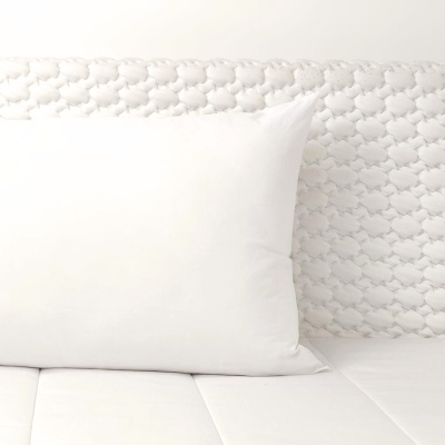 Travesseiro branco sobre colchão branco com padrão texturizado